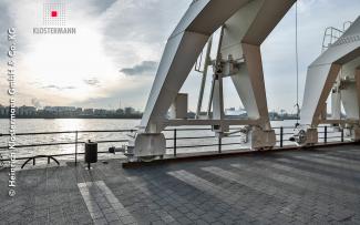 Nice to see the different finished surfaces of the specially developed paving stones made from copper slag. © Klostermann Cranes and quay with view onto the river