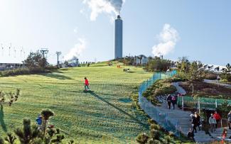 People skiing on synthetic mats on a pitched green roof